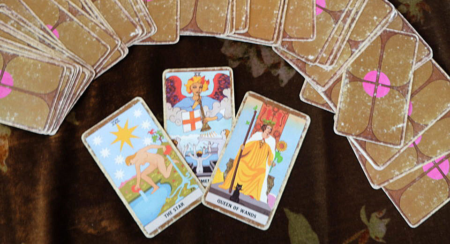 Photo shows three tarot cards face up, with the rest of the deck fanned out face down above them.